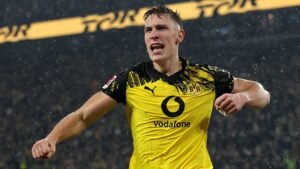 Nico Schlotterbeck célèbre avec véhémence sous son maillot du Borussia Dortmund, trempé par la pluie, illustrant l'intensité de l'atmosphère du match.