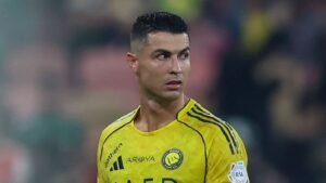 كريستيانو رونالدو يرتدي زي النصر الأصفر الزاهي، يبدو قلقاً خلال مباراة، مع خلفية ملعب ضبابية.