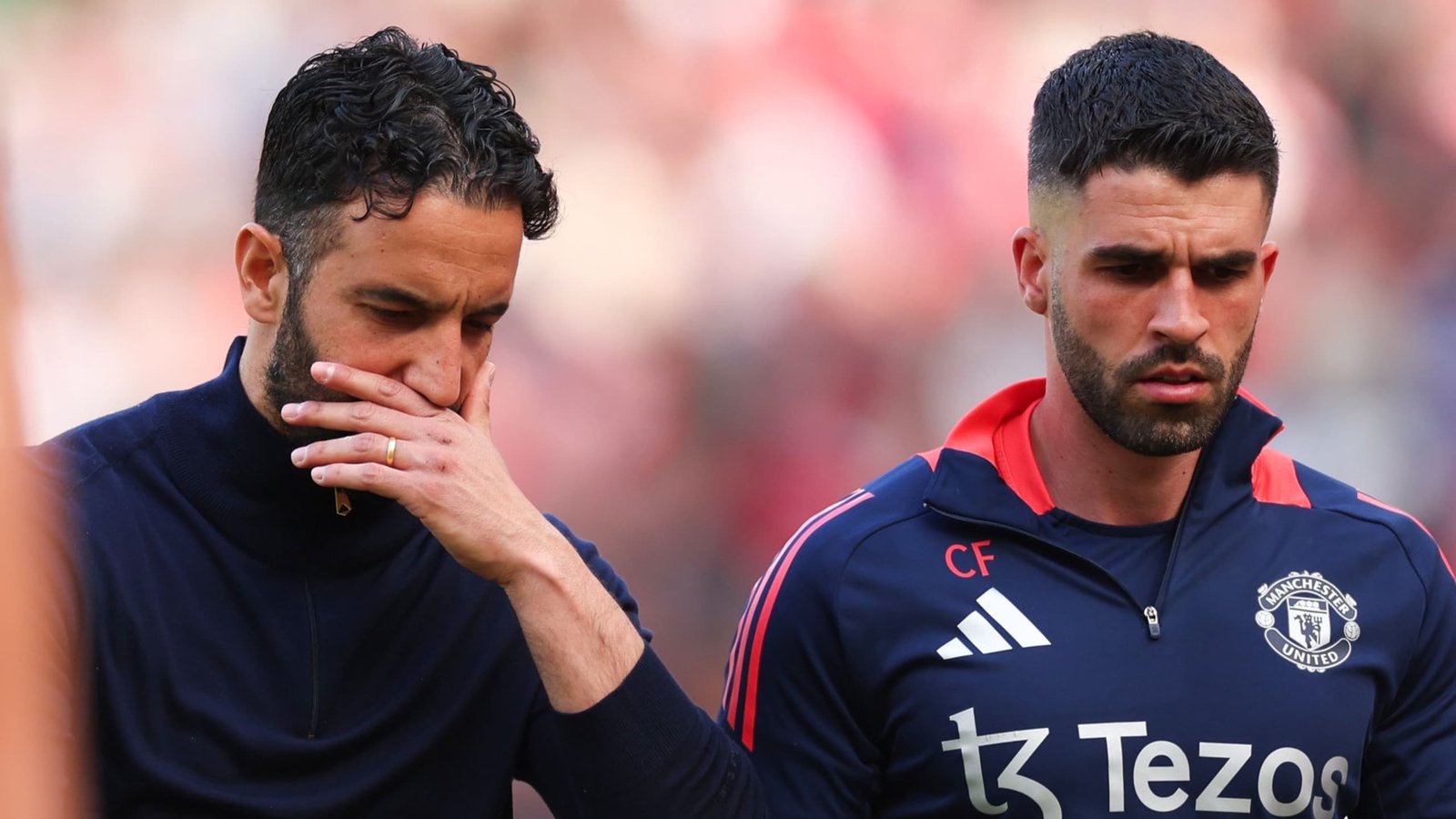 L'assistant de Ruben Amorim, plongé dans ses pensées, marche aux côtés d'un collègue à l'air solennel, vêtu de la tenue d'entraînement de Manchester United.