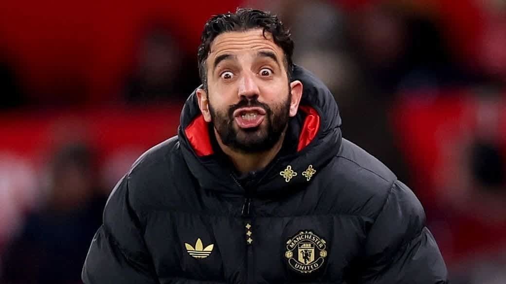 Ruben Amorim, vêtu d'une veste noire de Manchester United, affiche une expression surprise durant un match, illustrant les émotions intenses sur le bord du terrain.