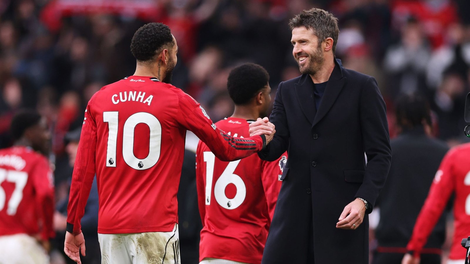 Cunha, gekleed in het rugnummer 10, schudt de hand van Manchester United-manager Michael Carrick, te midden van teamgenoten in rode tenues.