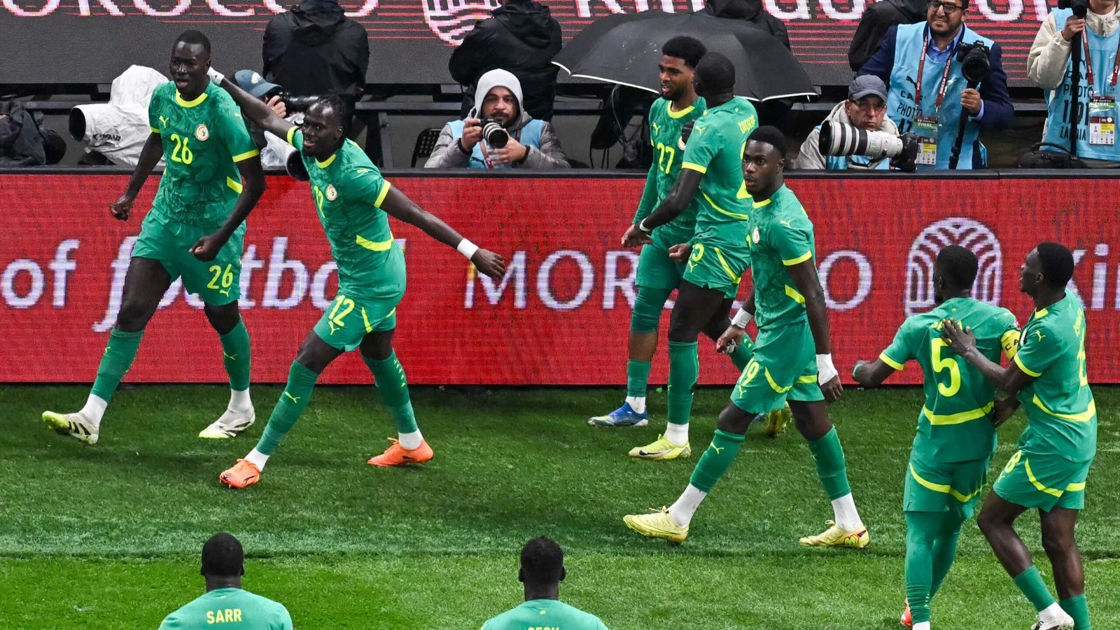 Les joueurs sénégalais célèbrent un but dans leurs tenues vert vif lors du match de la CAN 2025 contre le Maroc, démontrant l'unité et l'enthousiasme de l'équipe.