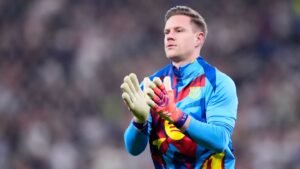 Marc-André ter Stegen, wearing a vibrant Barcelona kit, claps while preparing for the match, showcasing his goalkeeping gloves.