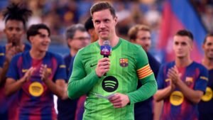 Marc-André ter Stegen vêtu du maillot vert du Barça, s'adressant aux supporters avec un micro, tandis que ses coéquipiers applaudissent à l'arrière-plan.