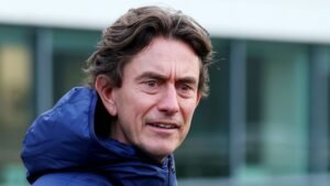 Thomas Frank, entraîneur de Brentford, l'air concentré, portant une veste bleue, dans un contexte de séance d'entraînement.