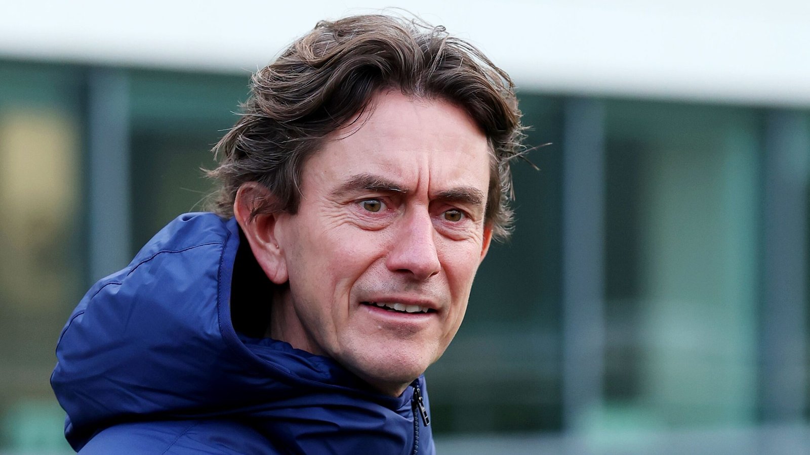 Thomas Frank, entraîneur de Brentford, l'air concentré, portant une veste bleue, dans un contexte de séance d'entraînement.