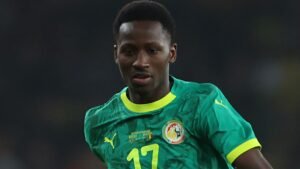 Senegalese speler in een levendig groen tenue met gele accenten, geconcentreerd op het spel tijdens de AFCON-finale.