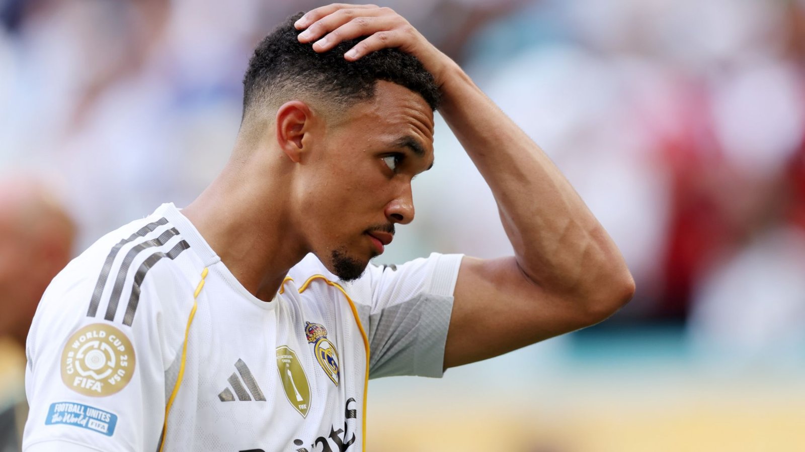 Trent Alexander-Arnold ziet er bedachtzaam uit, raakt zijn hoofd aan, gekleed in een Real Madrid-tenue tijdens een gespannen wedstrijdmoment.