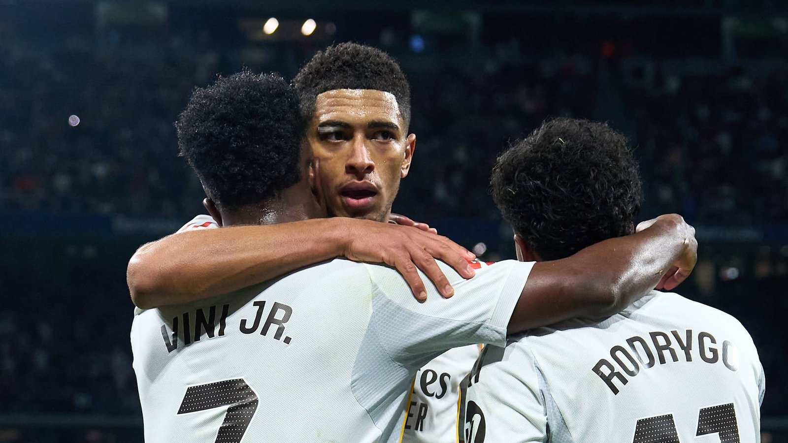 Bellingham célèbre avec Vinícius Jr. et Rodrygo après un match, illustrant leur unité et leur esprit d'équipe dans le maillot blanc du Real Madrid.