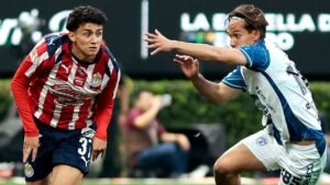 Un joueur de Chivas, en rayures rouges et blanches, évite un défenseur en bleu et blanc lors d'un moment tendu d'un match de championnat mexicain.