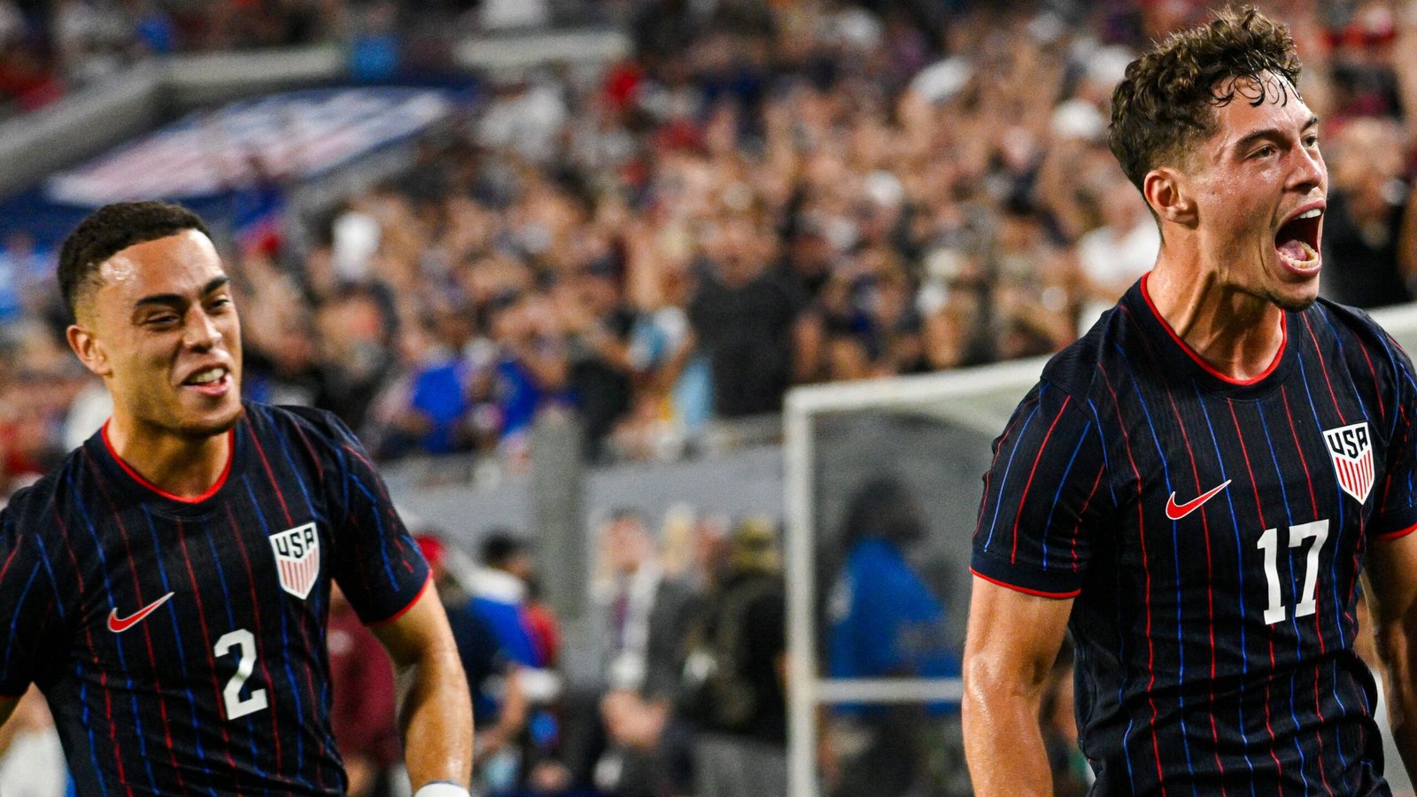 Des joueurs américains célébrant un but, portant leurs maillots rayés bleu marine et rouge, avec une foule enthousiaste en arrière-plan, illustrant l'esprit d'équipe.