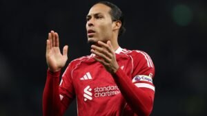 Virgil van Dijk in een rood Liverpool-tenue gebaart met zijn handen en toont vastberadenheid en leiderschap tijdens een wedstrijd.