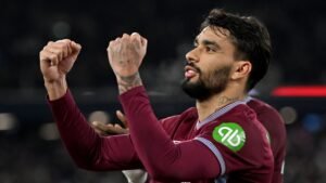 Lucas Paquetá viert een doelpunt in het bordeauxrood en blauw tenue van West Ham, toont enthousiasme met geheven vuisten in een stadionsetting.