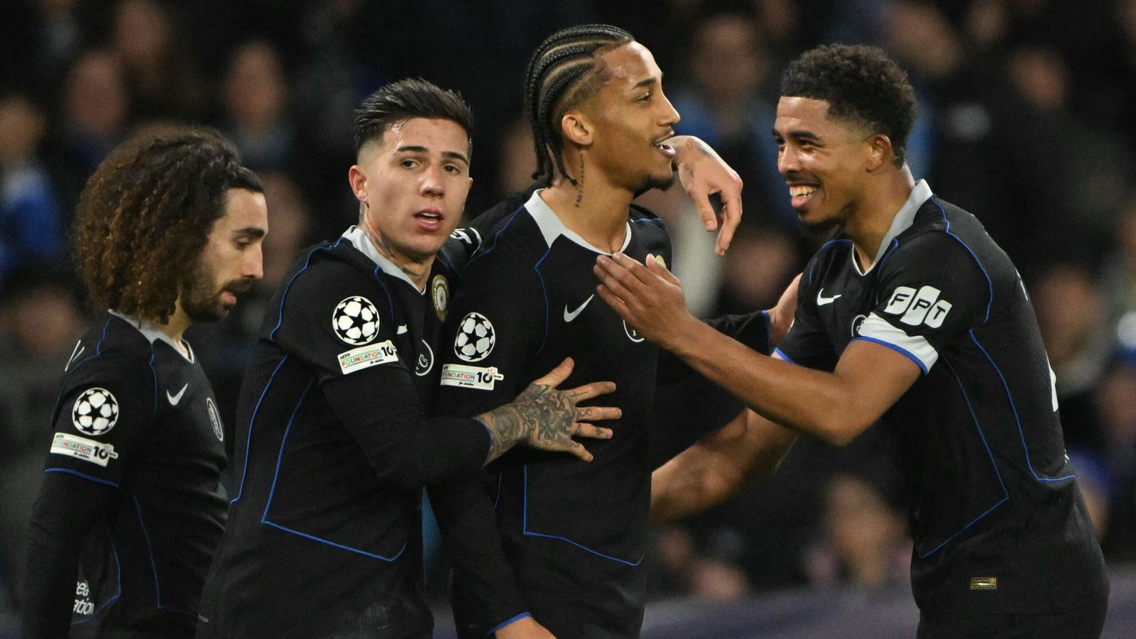 Chelsea-spelers die na een doelpunt juichen, in hun zwarte Champions League-tenues, tonen teamwork en opwinding tijdens een wedstrijd.