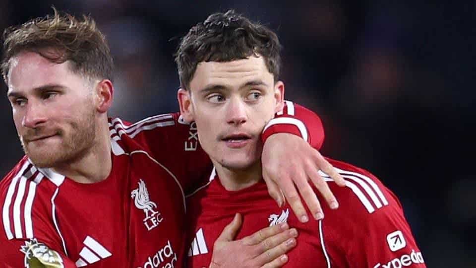 Liverpool players celebrate a goal together, wearing their iconic red kits with white accents, showcasing team camaraderie on the pitch.