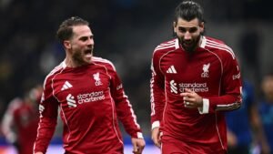 Les joueurs de Liverpool célèbrent avec joie dans leurs tenues rouges, manifestant leur enthousiasme après une action réussie lors d'un match.