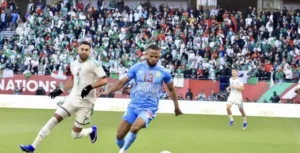 Le joueur marocain numéro 13 dribble un adversaire dans un stade vibrant rempli de supporters passionnés pendant un match.
