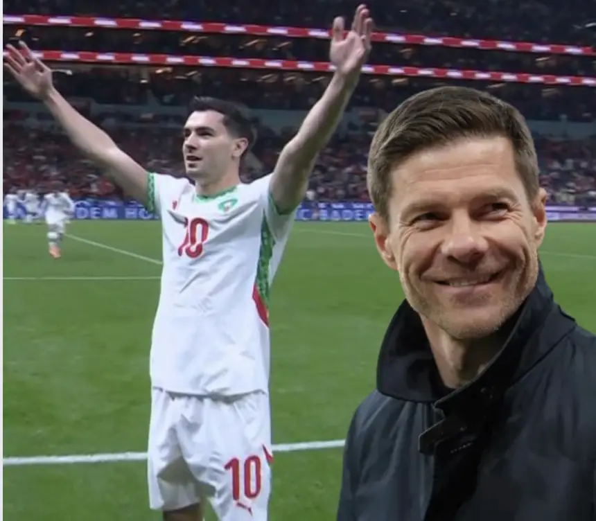 Moroccan player celebrating in a white kit with green and red details, while a smiling coach observes from the side during a match.