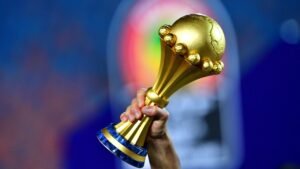 Golden Africa Cup of Nations trophy held aloft against a blurred backdrop, symbolising triumph in African football.