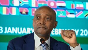 أحمد يحيى، رئيس الاتحاد الأفريقي لكرة القدم، يتحدث في مؤتمر صحفي مع عرض أعلام الدول الأفريقية في الخلفية.