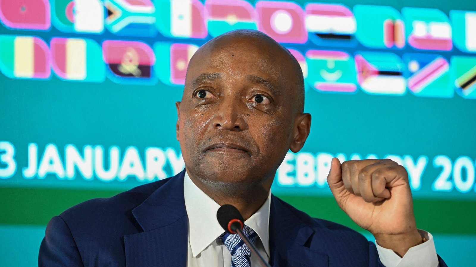 أحمد يحيى، رئيس الاتحاد الأفريقي لكرة القدم، يتحدث في مؤتمر صحفي مع عرض أعلام الدول الأفريقية في الخلفية.