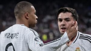 Kylian Mbappé embraces a teammate in a Real Madrid kit, celebrating during a UEFA tournament match, showcasing teamwork and excitement.