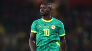 Sadio Mané in Senegal's vibrant green kit with yellow accents, focused during a match, highlighting his influential presence on the pitch.