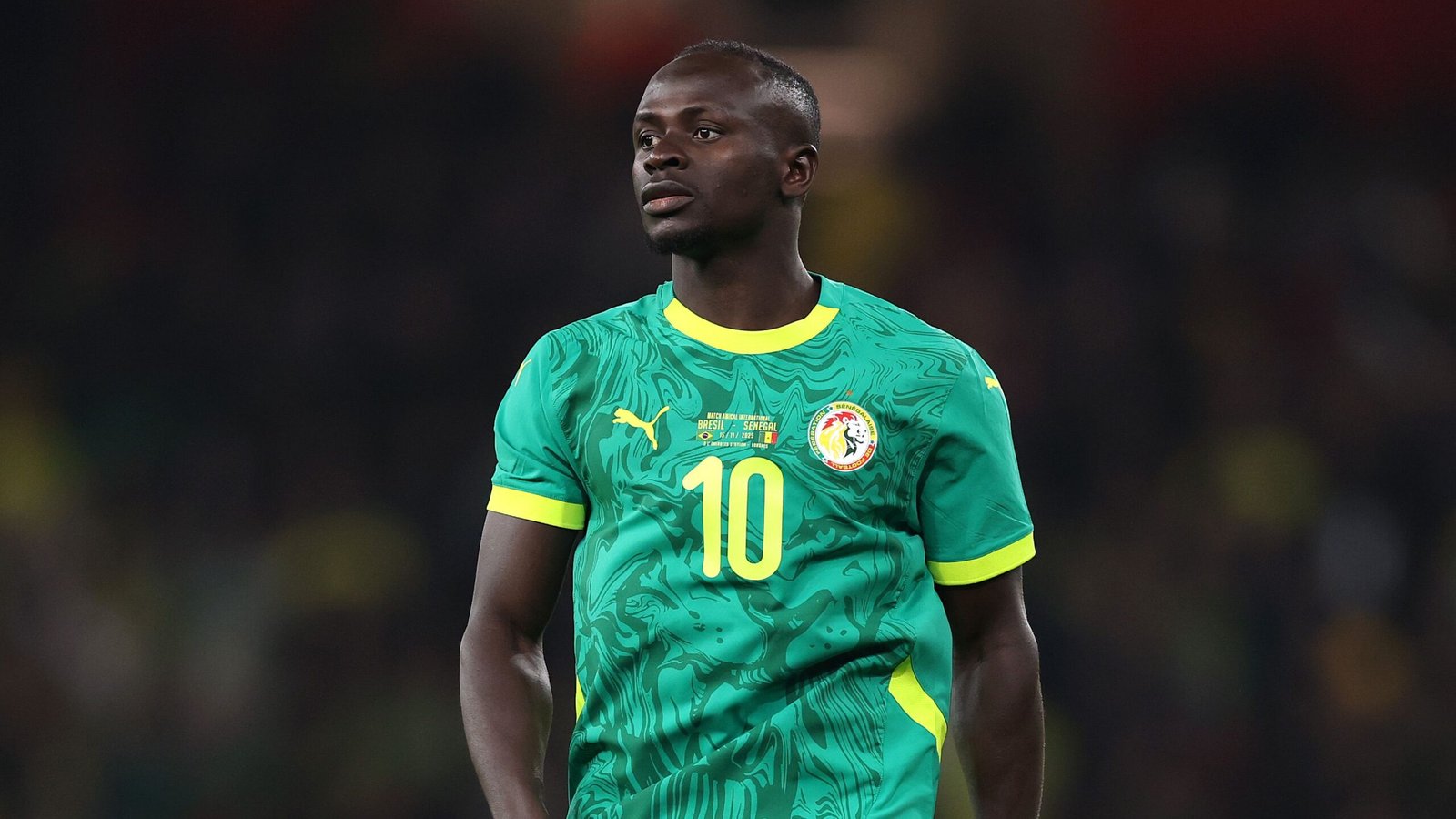 Sadio Mané in Senegal's vibrant green kit with yellow accents, focused during a match, highlighting his influential presence on the pitch.