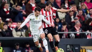 Real Madrid's player number 21 clashes with Athletic Bilbao's number 20, amid a lively crowd in a competitive match.
