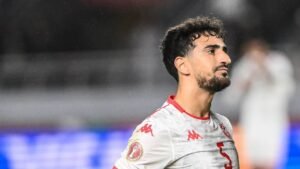 Tunisia's player, wearing a white kit with red accents and the number 5, gazes intently, reflecting the intensity of the match.