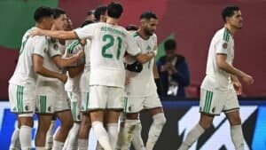 Morocco's national team celebrates a goal, wearing their white kit with green accents, during a match at a major tournament.