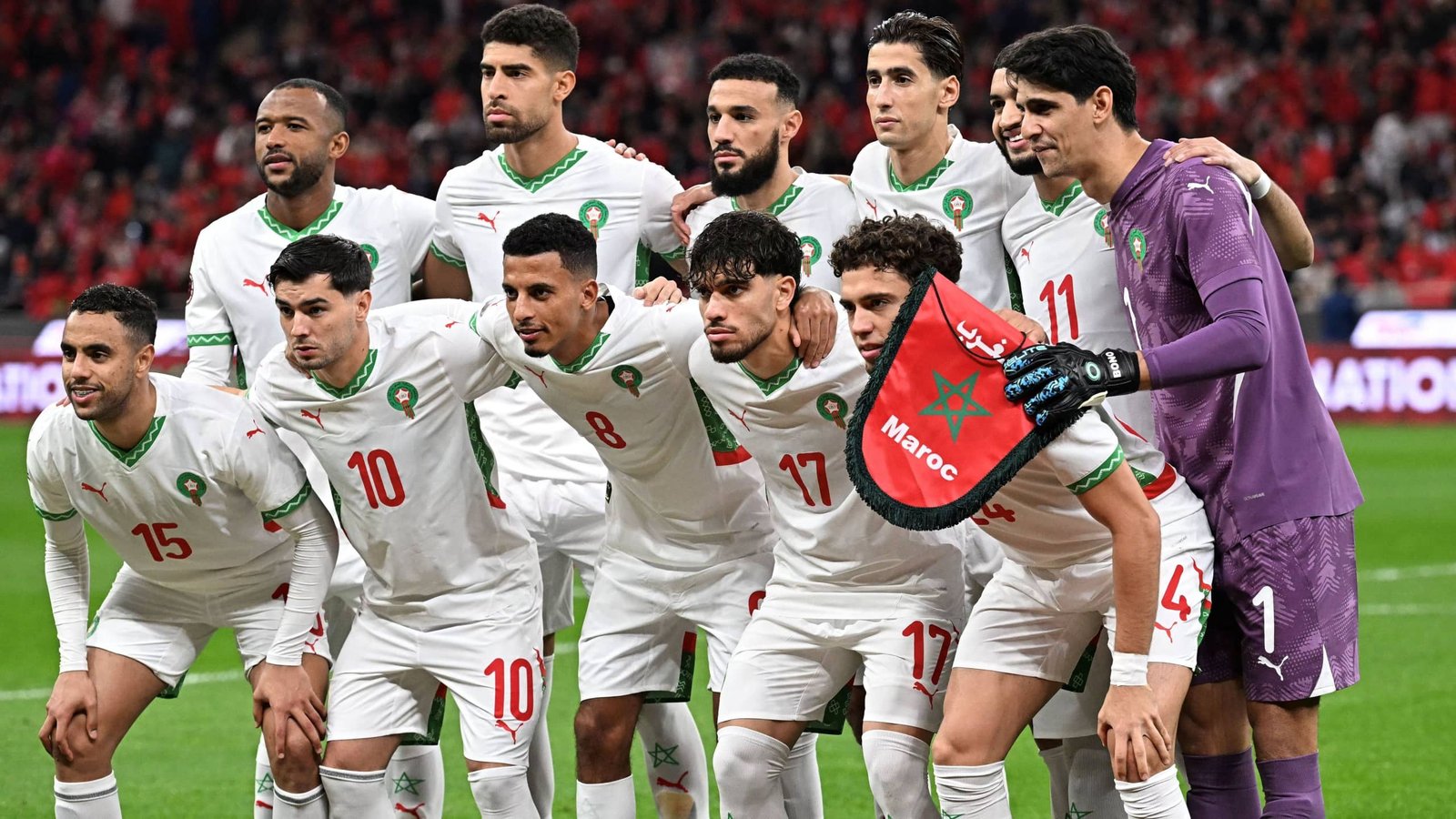 Morocco's national football team poses for a group photo, wearing white kits with green accents, ahead of an international match.