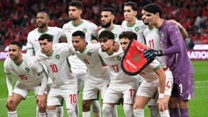Morocco's national football team poses for a group photo, wearing white kits with green accents, celebrating their unity before a match.