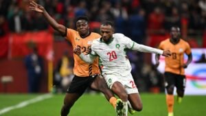 Morocco's player, wearing number 20, battles for the ball against an opponent in an orange kit during an intense match.