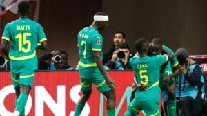 Les joueurs sénégalais célèbrent dans leurs kits verts vifs avec des accents jaunes, mettant en vedette Diatta, Gana et Oliviera, capturant un moment joyeux.