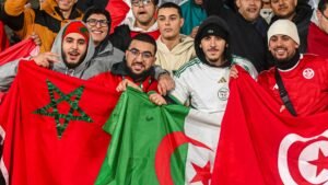 Les fans de football affichent fièrement les drapeaux marocain, algérien et tunisien, montrant l'unité et la passion pendant un match.