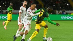Tunisia's players in white clash with Malawi's Aleng in a tense moment during the AFCON match, highlighting the competitive spirit of African football.