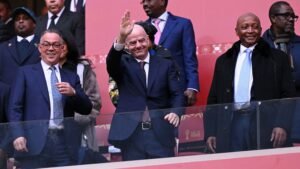 Le président de la FIFA, Gianni Infantino, salue les supporters, encadré par des officiels de la Fédération marocaine de football, lors d'un événement footballistique majeur.