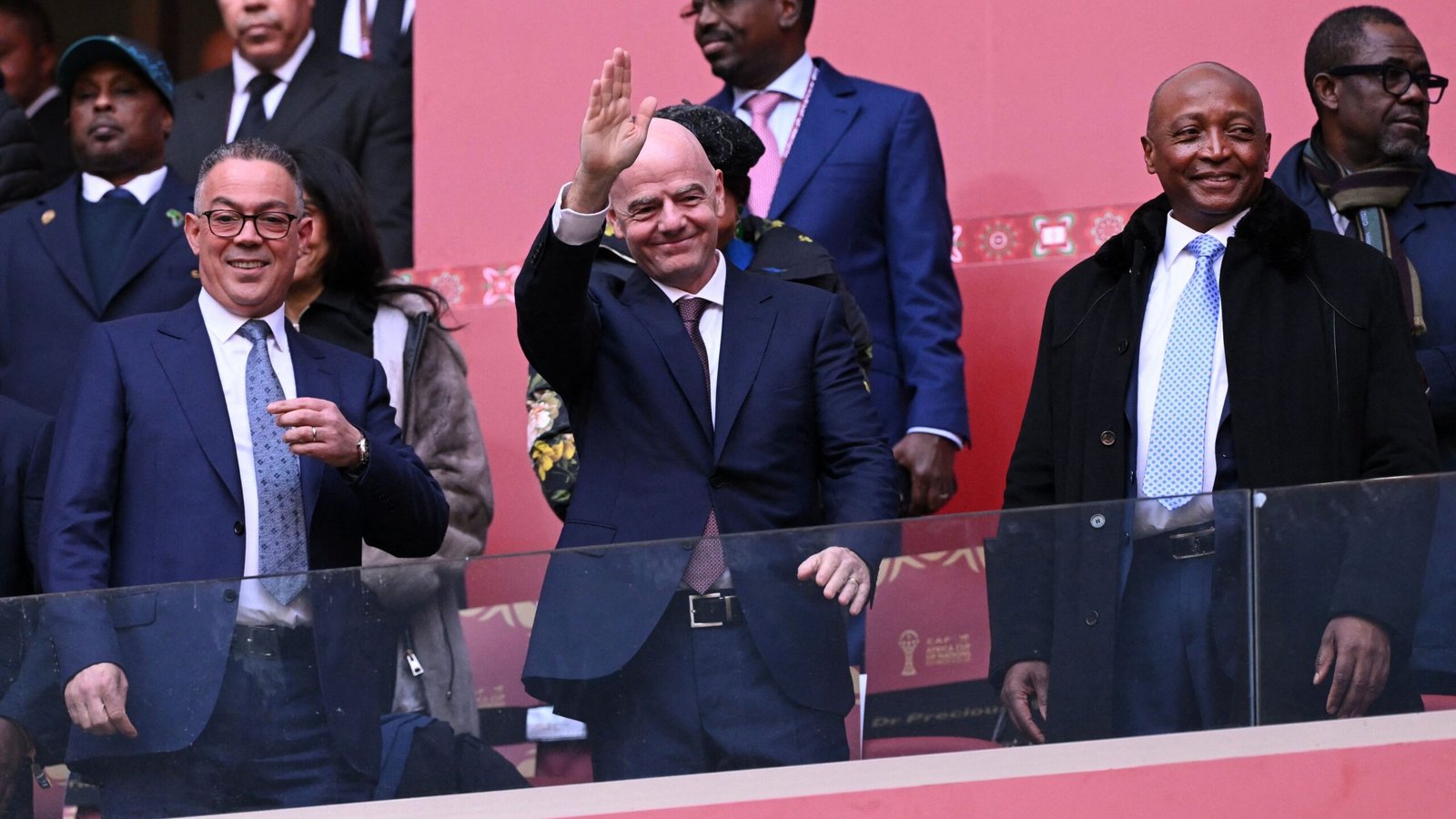 Le président de la FIFA, Gianni Infantino, salue les supporters, encadré par des officiels de la Fédération marocaine de football, lors d'un événement footballistique majeur.