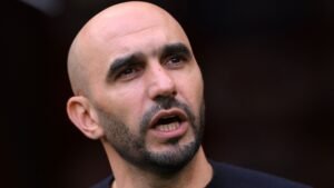 Walid Regragui responding passionately, with a serious expression, showcasing his role as the Moroccan national football team's manager.