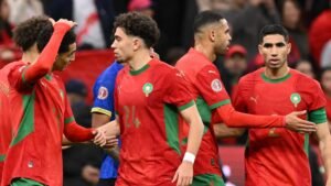 Les joueurs marocains en maillots rouges célèbrent ensemble sur le terrain, montrant la camaraderie lors d'un match international.