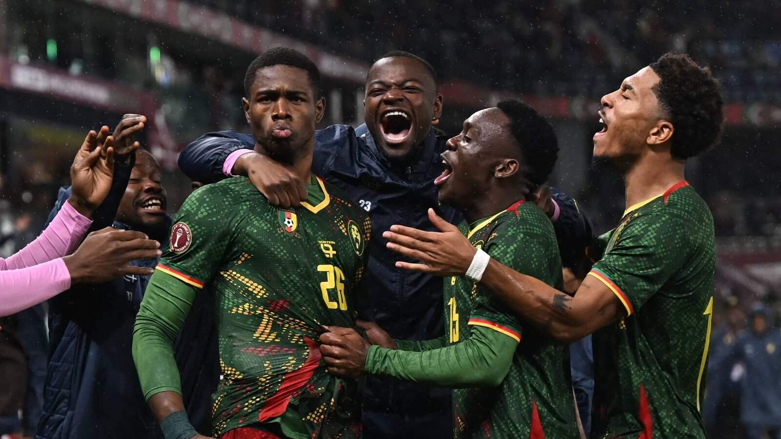 Cameroon players celebrate passionately, wearing their vibrant green kits. Emotions run high as they express joy after a key match moment.