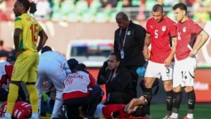 Les joueurs égyptiens en maillots rouges observent avec inquiétude le staff médical s'occuper d'un coéquipier blessé sur le terrain pendant le match.