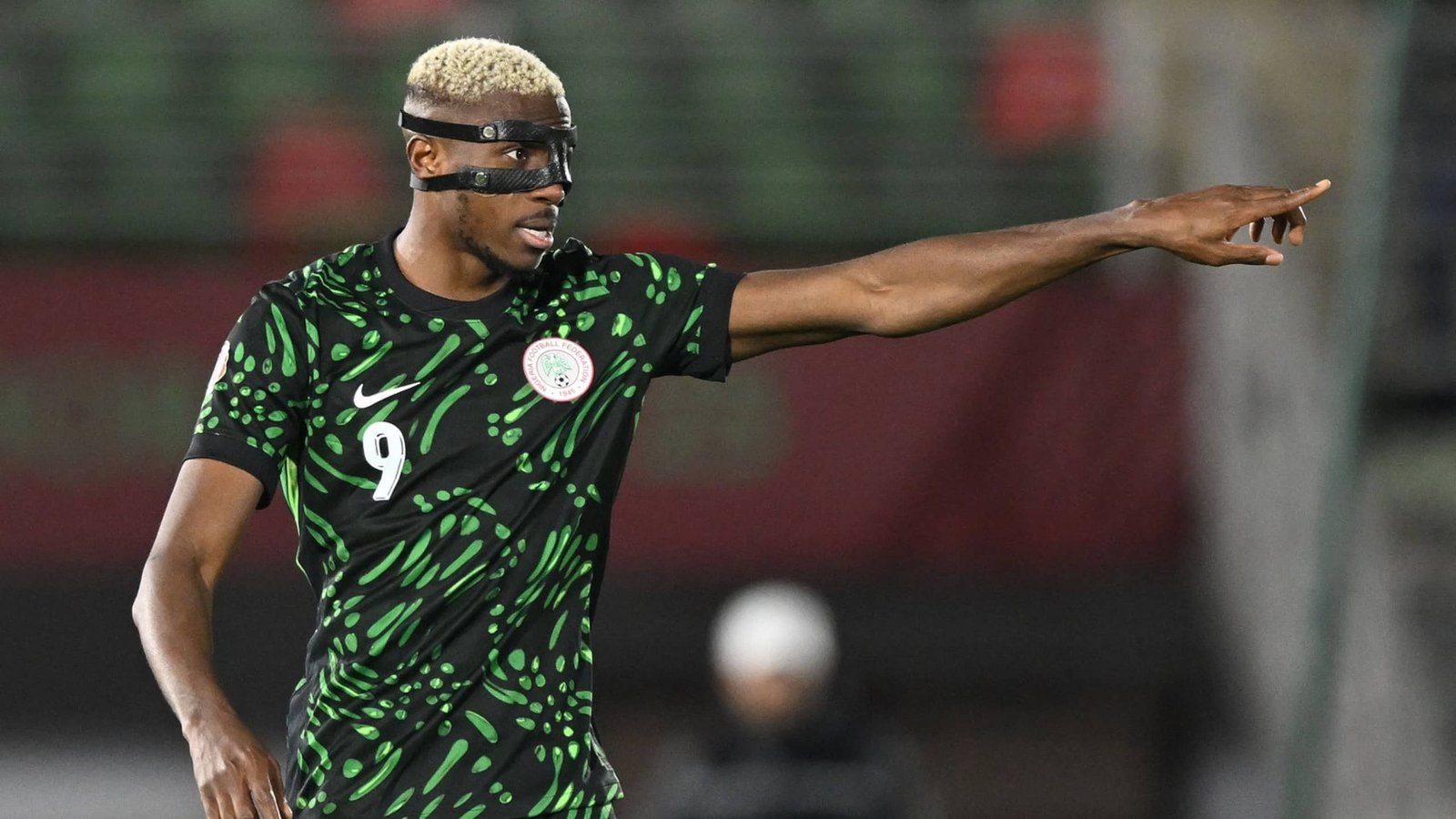 Victor Osimhen fait des gestes pendant un match, portant le maillot vert vif du Nigeria avec des motifs noirs, mettant en évidence sa concentration et son intensité.