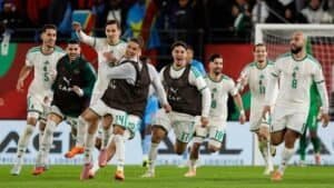 Les joueurs marocains célèbrent joyeusement après avoir marqué, portant des tenues blanches avec des accents verts. L'arrière-plan vibrant du stade renforce l'excitation.