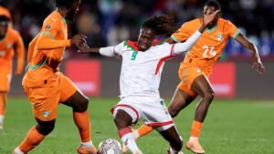 Le joueur marocain numéro 9 défie les adversaires ivoiriens lors d'un match dynamique, illustrant la compétition vibrante du football africain.