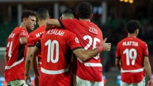 Les joueurs marocains M. Salah et Zizo s'embrassent en célébration, portant leurs maillots rouges, pendant un moment tendu dans un match.