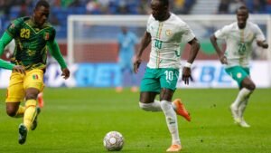 Senegal's number 10 player dribbles the ball against a Malian defender in colourful kits during an intense match, showcasing vibrant action.