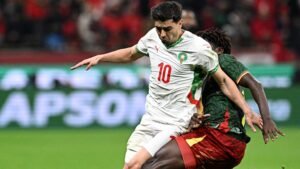 Le numéro 10 du Maroc dribble un défenseur camerounais lors d'un match tendu, montrant l'intensité de la compétition de football africain.