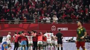 Les joueurs marocains célèbrent un but important, entourés de fans jubilants en tenue rouge lors d'un match international contre le Cameroun.